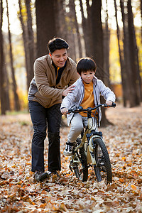 秋天户外父亲教儿子骑自行车图片