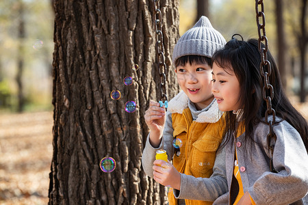 快乐儿童在户外荡秋千上一起吹泡泡和聊天图片