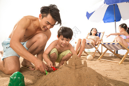 拿着铲子女孩幸福家庭在沙滩上玩耍背景