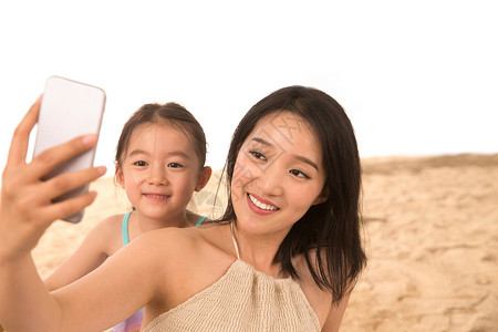 母亲和女儿在沙滩上拍照图片