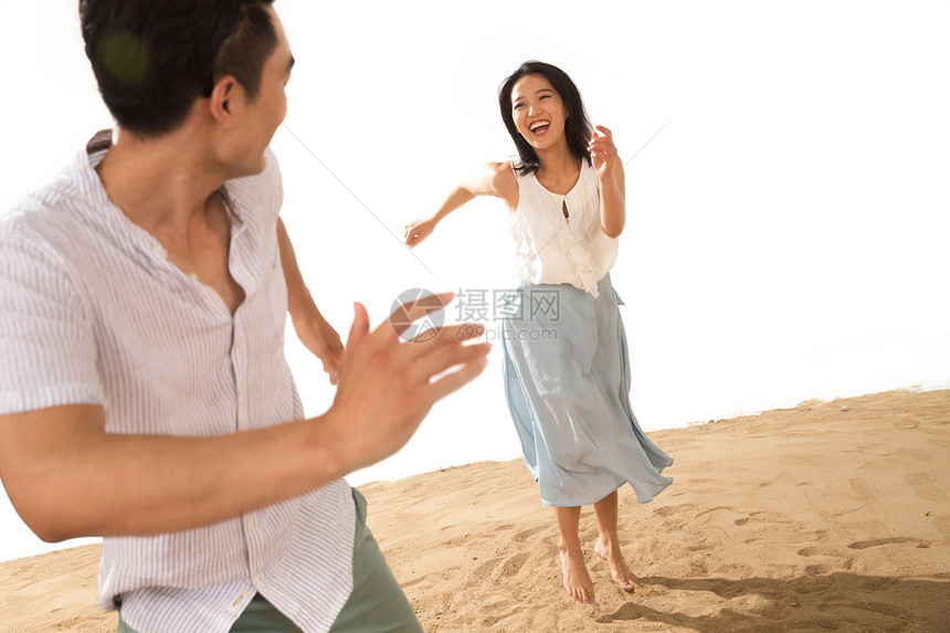 年轻情侣在沙滩上玩耍图片