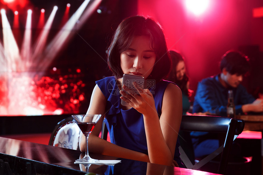 青年女人在酒吧看手机图片