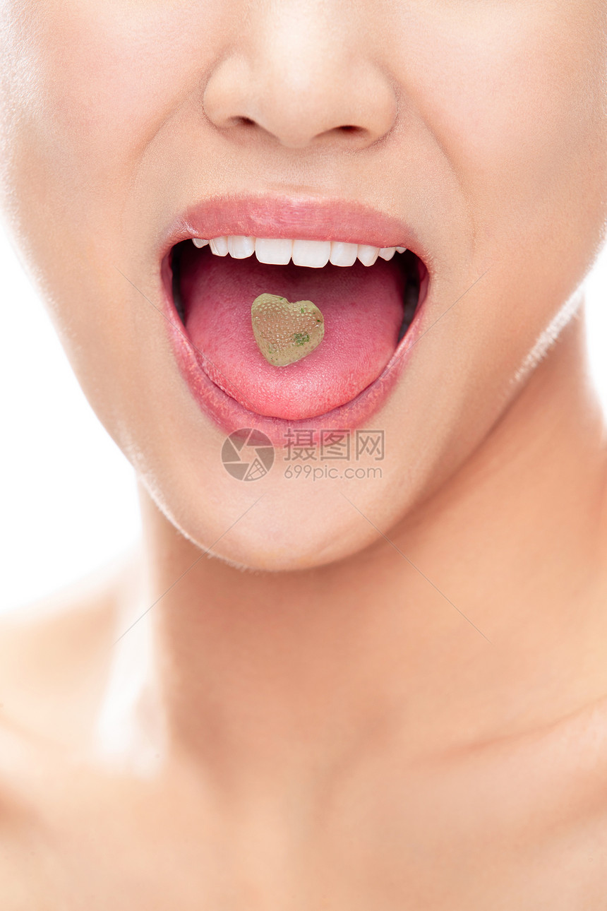 舌头上有颗心形糖的青年女人嘴部特写图片