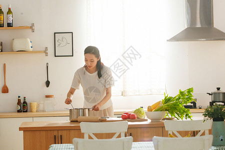 制作轻松的青年女人在厨房里做饭背景