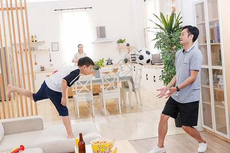 头球父亲和儿子在家玩足球背景