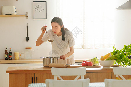 制作轻松的青年女人在厨房里做饭背景