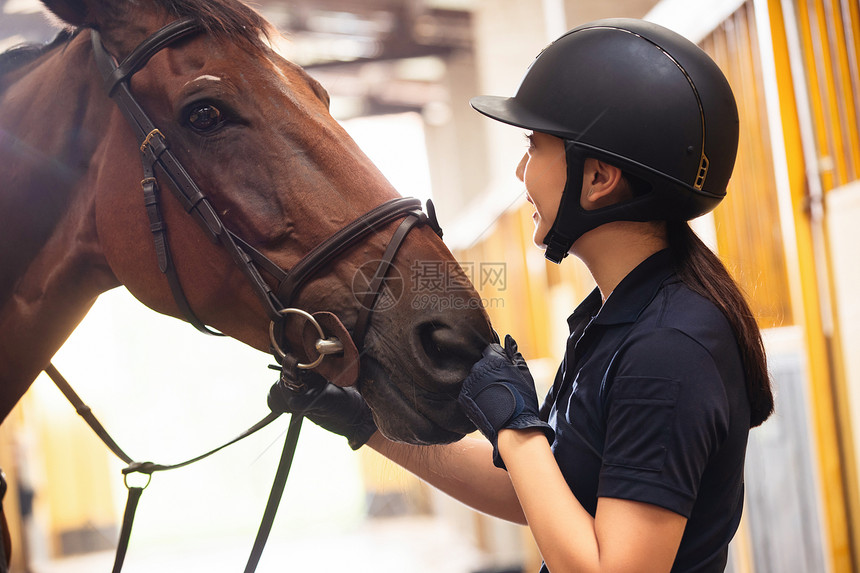 马厩里安抚马的年轻女子图片
