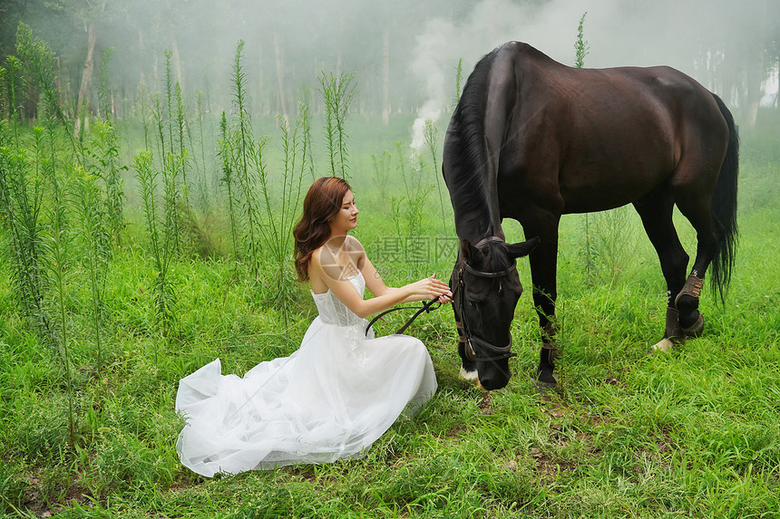 草地上穿着婚纱的青年女人和马图片
