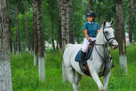 林间路上帅气的女孩骑着马图片