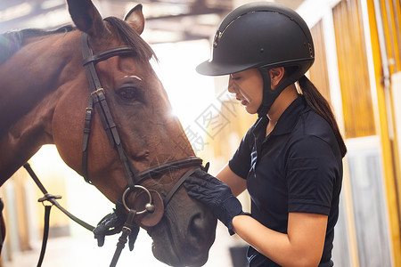 关爱马的漂亮年轻女人在马厩走廊高清图片
