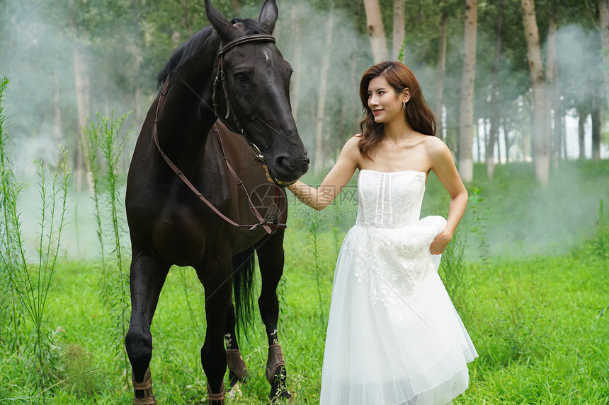 树林里漂亮的青年女人牵着马图片