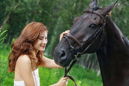户外漂亮的年轻女人抚摸着马图片