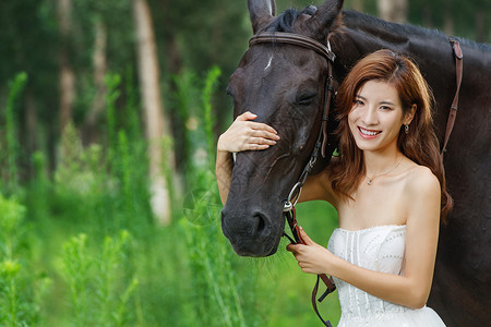 前景草草丛中漂亮的青年女人搂着马背景