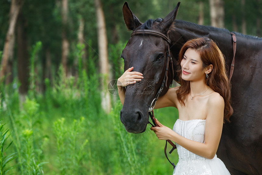 户外漂亮的青年女人搂着马图片