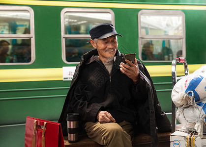 在火车站台上用手机的老人背景图片