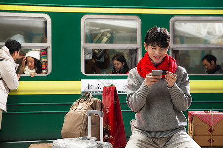 手机购票在火车站台上用手机的青年男人背景