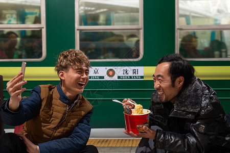 两名男子在火车月台上看手机高清图片