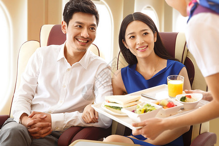 安全用餐年轻夫妇在飞机上用餐背景