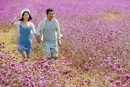 在麦田里奔跑的情侣青年夫妇手牵手在花海里奔跑背景