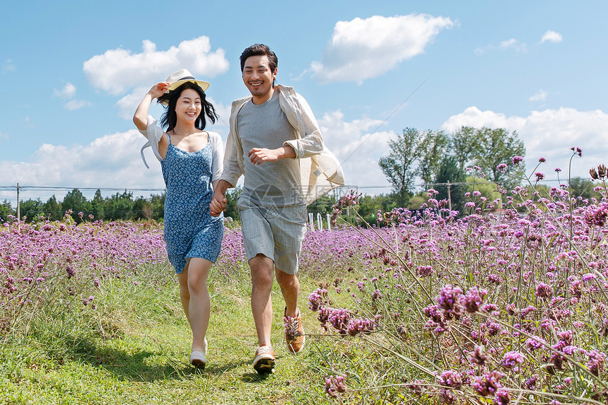 青年夫妇手牵手在花海里奔跑图片