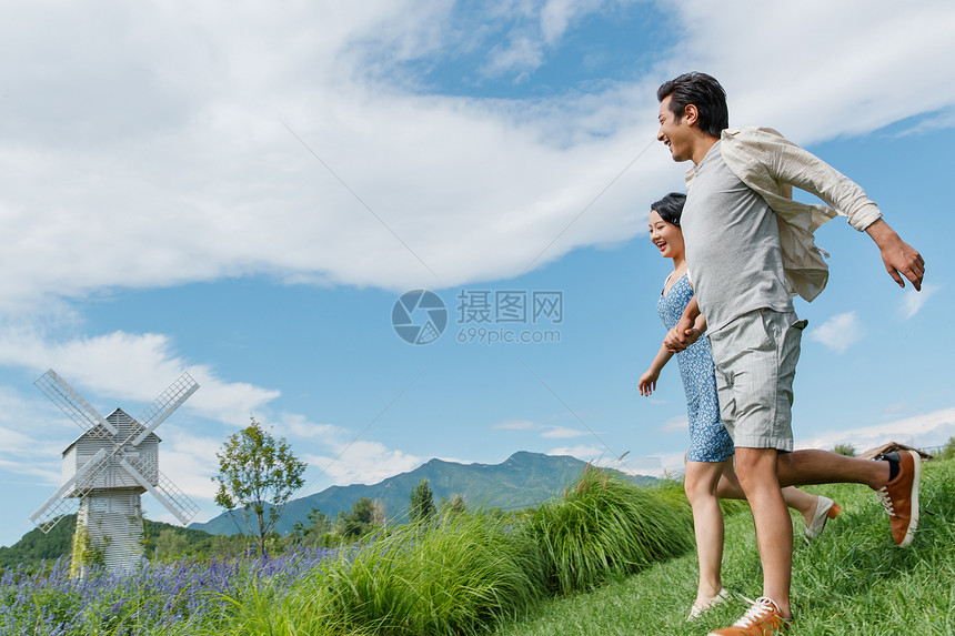 浪漫夫妇手牵手在草地上奔跑图片