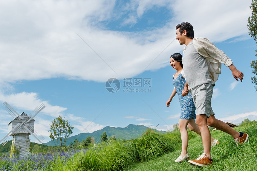 浪漫夫妇手牵手在草地上奔跑图片