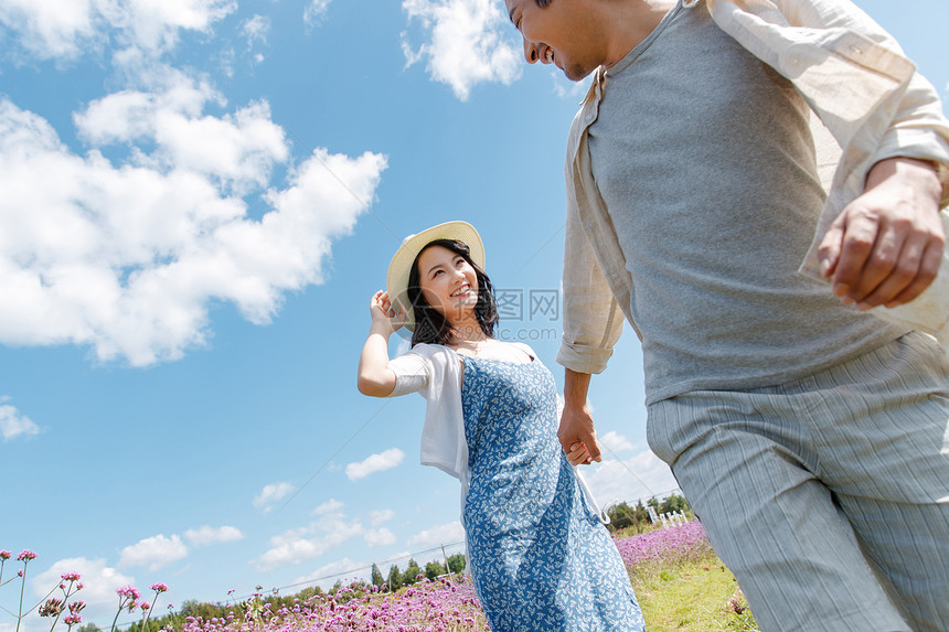 青年夫妇手牵手在花海里奔跑图片