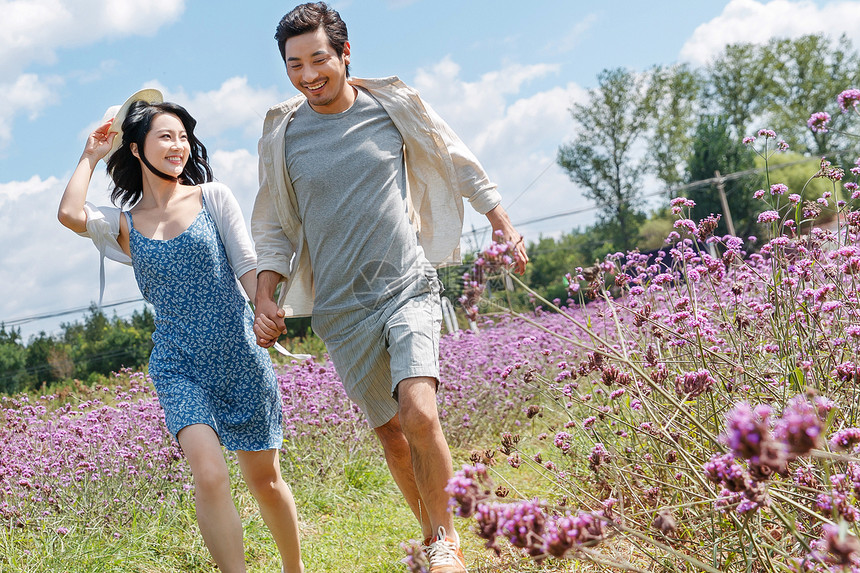 青年夫妇手牵手在花海里奔跑图片