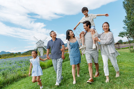 带小孩看大风车在草地上散步的幸福家庭背景