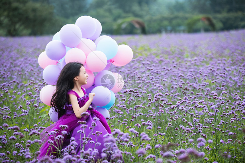 拿着气球的小女孩在花海里奔跑图片