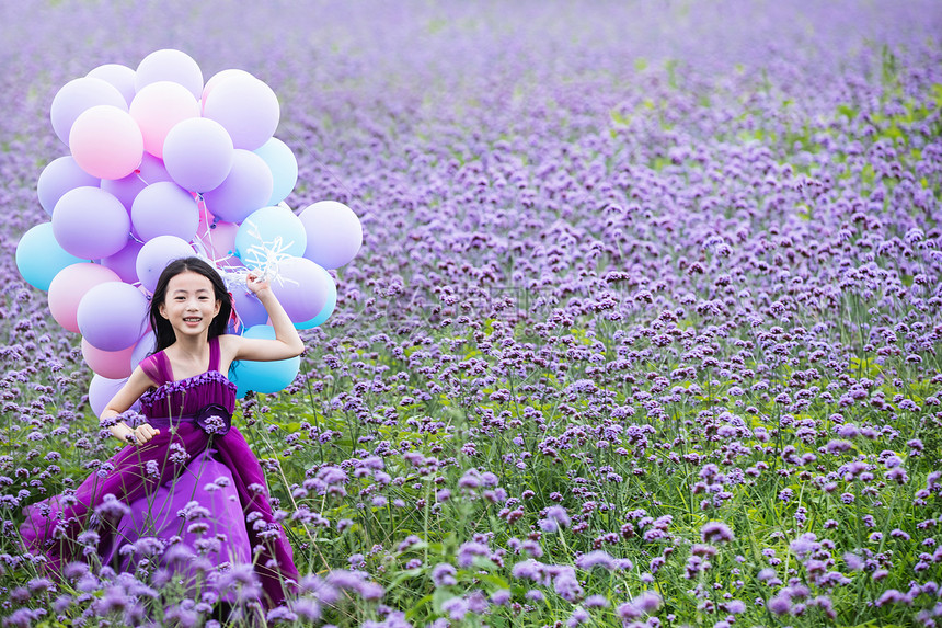 拿着气球的小女孩在花海里奔跑图片