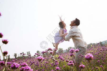 父亲抱着女儿在花丛中玩耍高清图片