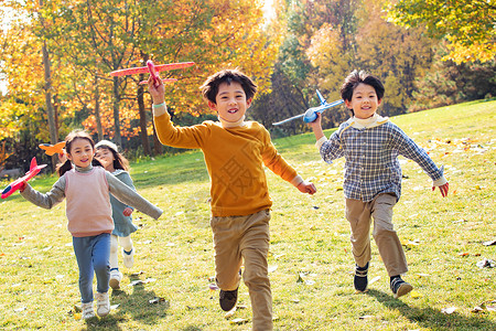 快乐儿童拿着玩具飞机在公园玩耍图片