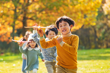 快乐儿童拿着玩具飞机在公园玩耍高清图片