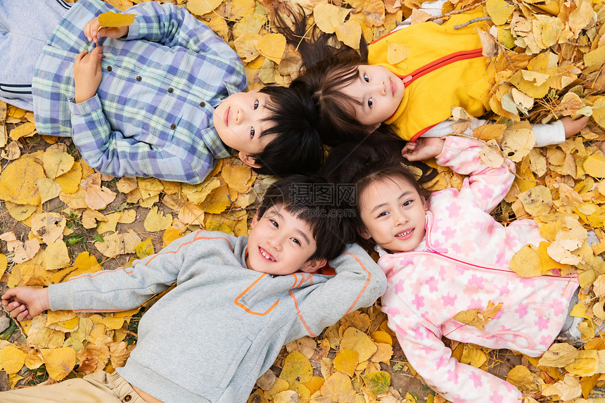 可爱的小朋友们躺在落叶上玩耍图片