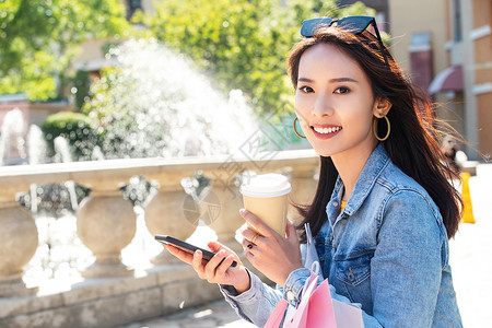青年女人拿着手机逛街图片