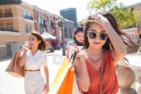 快乐的青年女人和闺蜜逛街购物太阳镜高清图片素材