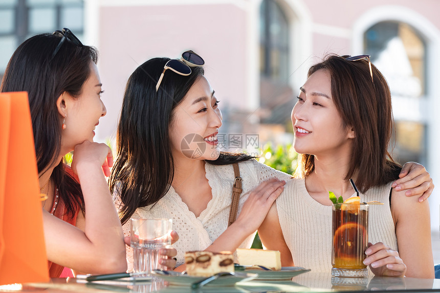 漂亮年轻的女孩们坐在路边咖啡馆聊天图片