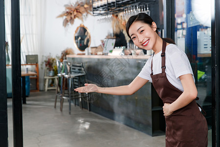 站着咖啡店门口做欢迎手势的女服务员背景图片