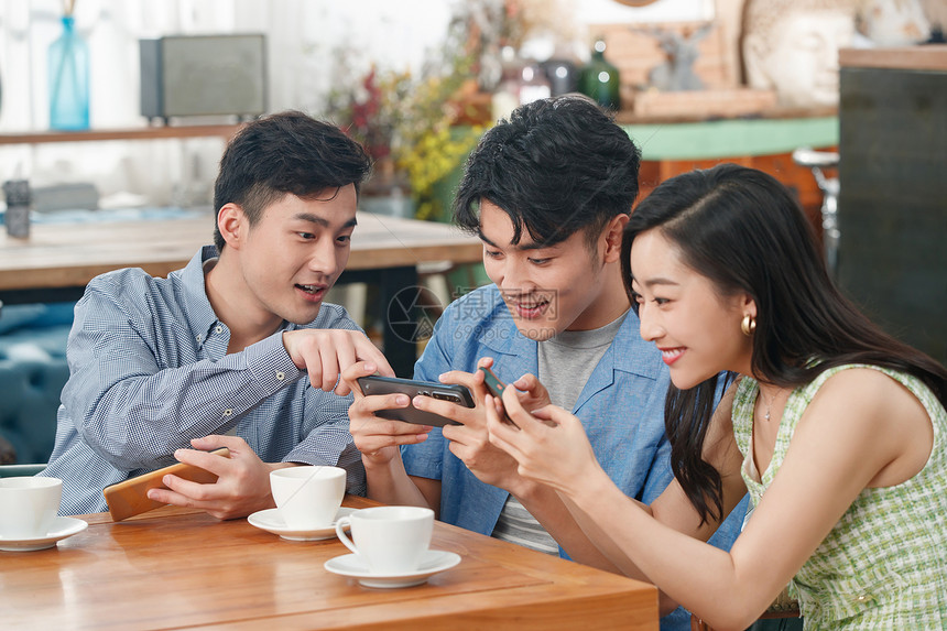 年轻朋友在咖啡馆里玩手机图片