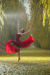 向上跳穿红色裙子的青年女人在户外跳芭蕾舞背景