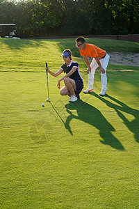 球场上教练指导青年女人打高尔夫高清图片