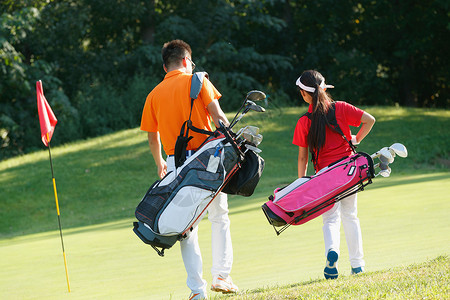 儿童步行球场上教练和学生背着高尔夫球包步行的背影背景