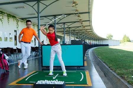 练习场上教练指导女童打高尔夫高清图片