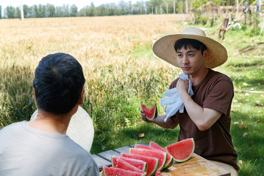 农民在田地旁休息吃西瓜图片