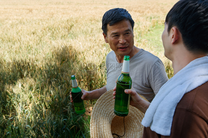 农民在麦田旁喝啤酒图片
