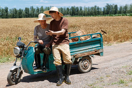 农民坐在三轮车上使用手机背景