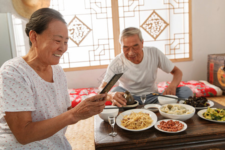 农村饺子老年夫妇在家里吃饭看手机背景