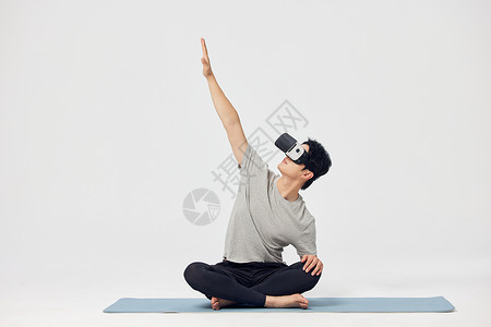 教学科技在瑜伽垫上戴着vr眼镜锻炼的男性背景