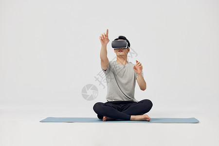人工智能健身坐在瑜伽垫上操作vr设备的男性背景